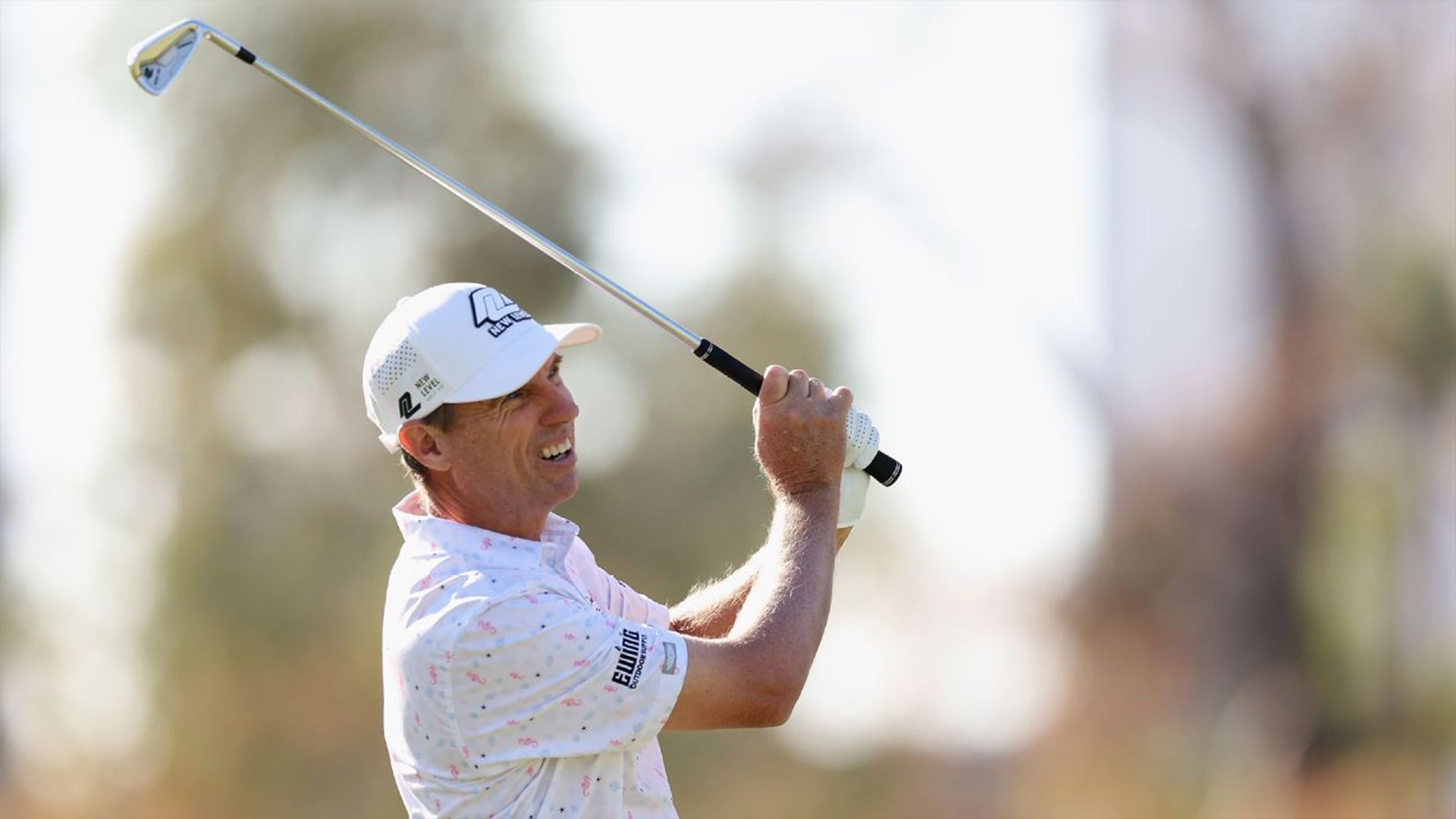 Steven Alker smiles through his follow-through on an iron shot wearing a Straight Down printed polo