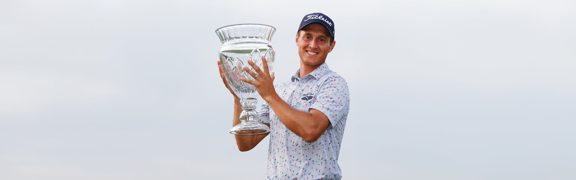 Tim Widing, Straight Down ambassador, holds the crystal Korn Ferry Tour trophy aloft with a smile, wearing a Straight Down printed polo