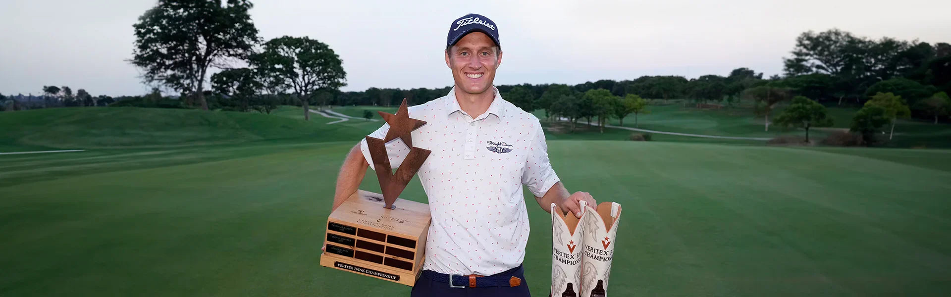 Tim Widing celebrates his Korn Ferry Tour victory at the Veritex Bank Championship, holding the trophy and winner's cowboy boots on the course at dusk, wearing a Straight Down polo.