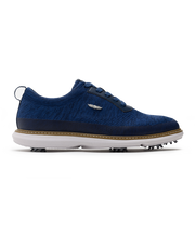 Men's Challenger Shoe in Indigo, side profile view featuring a navy knit upper with navy laces, a silver wing logo badge, navy leather trim, a tan welt stitch detail, white midsole, and spiked outsole