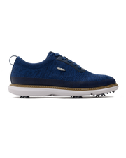 Men's Challenger Shoe in Indigo, side profile view featuring a navy knit upper with navy laces, a silver wing logo badge, navy leather trim, a tan welt stitch detail, white midsole, and spiked outsole