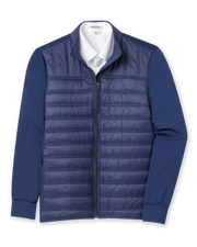 Men's Patton Jacket in Indigo, flat lay front view featuring a solid navy quilted insulated body with knit sleeves, full zip closure, stand collar, and side zip pocket