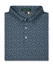 Men's Redbud Polo in New Indigo, folded flat lay front view featuring a navy base with a scattered green and light pink floral print