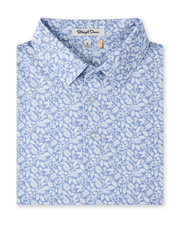 Close-up product view of the Tropics Lounge Polo in Blue Shade, featuring an allover white botanical print on a light blue background and a three-button placket.