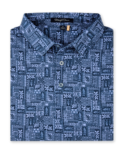 Folded Reef Runner Polo in Blue Shade, featuring an allover patchwork-inspired print with fish, florals, leaves, and geometric motifs.