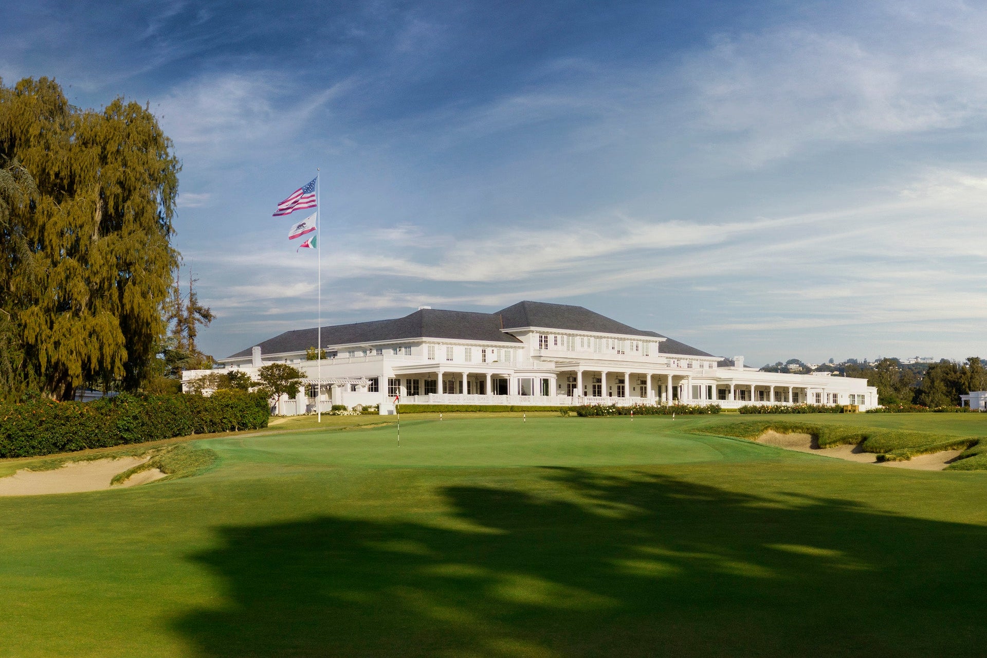 The iconic white clubhouse at Los Angeles Country Club's North Course, with the American and California flags flying above the 18th green ahead of the 123rd U.S. Open.