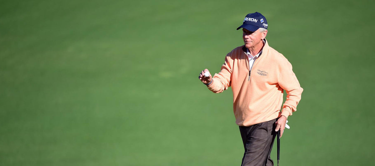 Larry Mize walks across the fairway at Augusta National during a Masters practice round, holding a golf ball in his hand