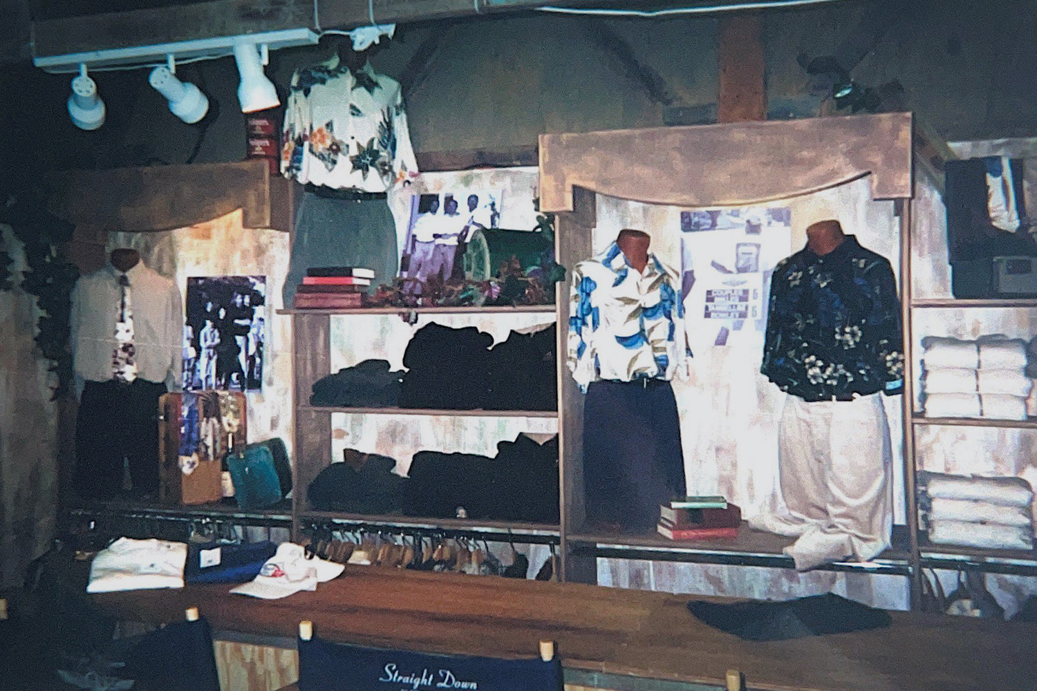 A vintage photo of Straight Down's original retail store interior in San Luis Obispo, featuring mannequins displaying tropical print apparel and folded merchandise on wooden shelving.