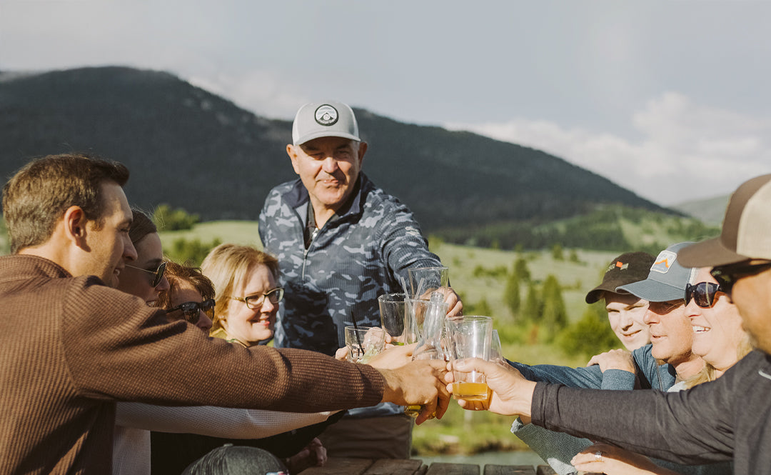 Mike Rowley raises a toast with family and friends against a scenic mountain backdrop.