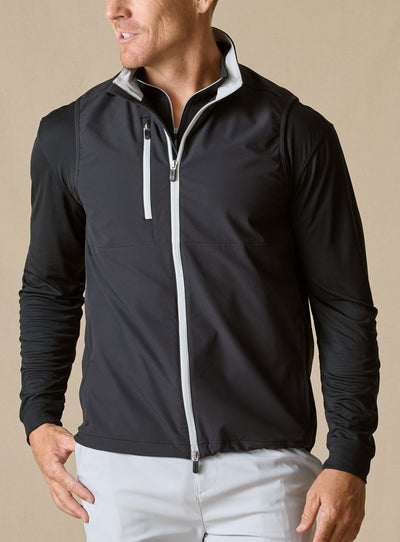 Men's Denver Vest in Black, front model view featuring a black shell with light gray contrast full-zip closure and zippered chest pocket, layered over a black long sleeve pullover with light gray pants
