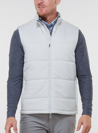 Men's Canyon Vest in Silver, front on-model view featuring a light gray quilted puffer vest with a full zip closure, styled with a charcoal heather long sleeve and gray pants