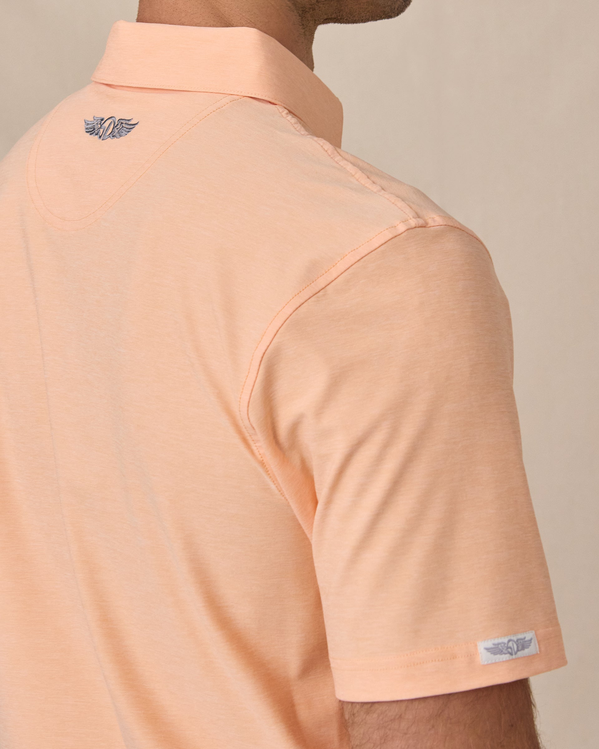 Close-up back detail of Dodge Polo in Cantalope Orange with embroidered neck logo