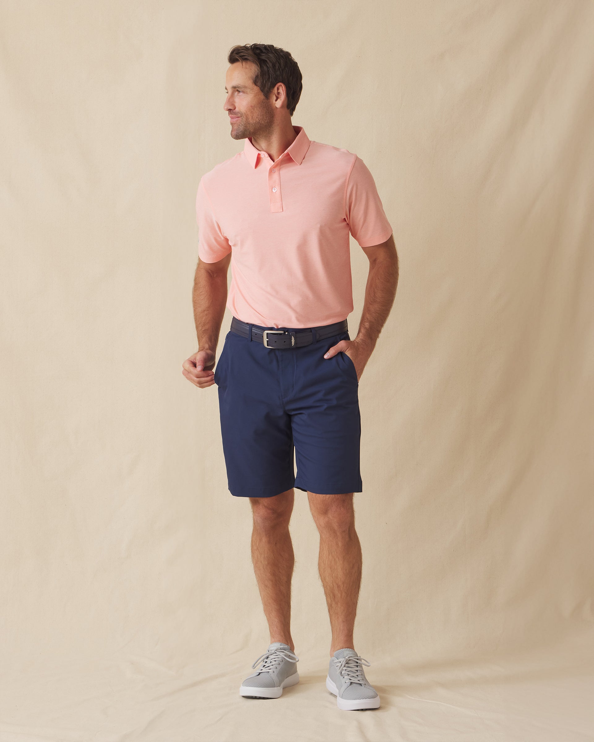 Dodge Polo in Spritz Orange, full-body lifestyle model view styled with navy shorts