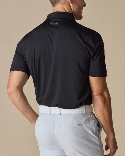 Men’s Olympic Polo in Black, back view worn with light golf pants