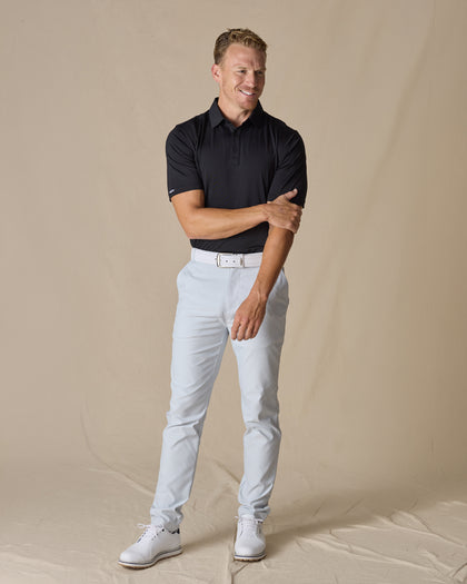 Men’s Olympic Polo in Black, full-body styling view with light golf pants and white golf shoes