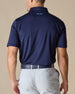 Men’s Olympic Polo in Indigo Blue, back view worn with light golf pants