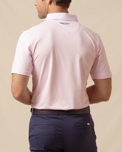 Back view of men’s solid lilac polo with collar logo detail, tucked into navy shorts