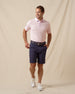 Men’s lilac polo styled with navy shorts, brown belt, and white sneakers