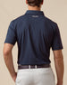 Back view of men’s solid blue polo with collar logo detail, tucked into silver shorts
