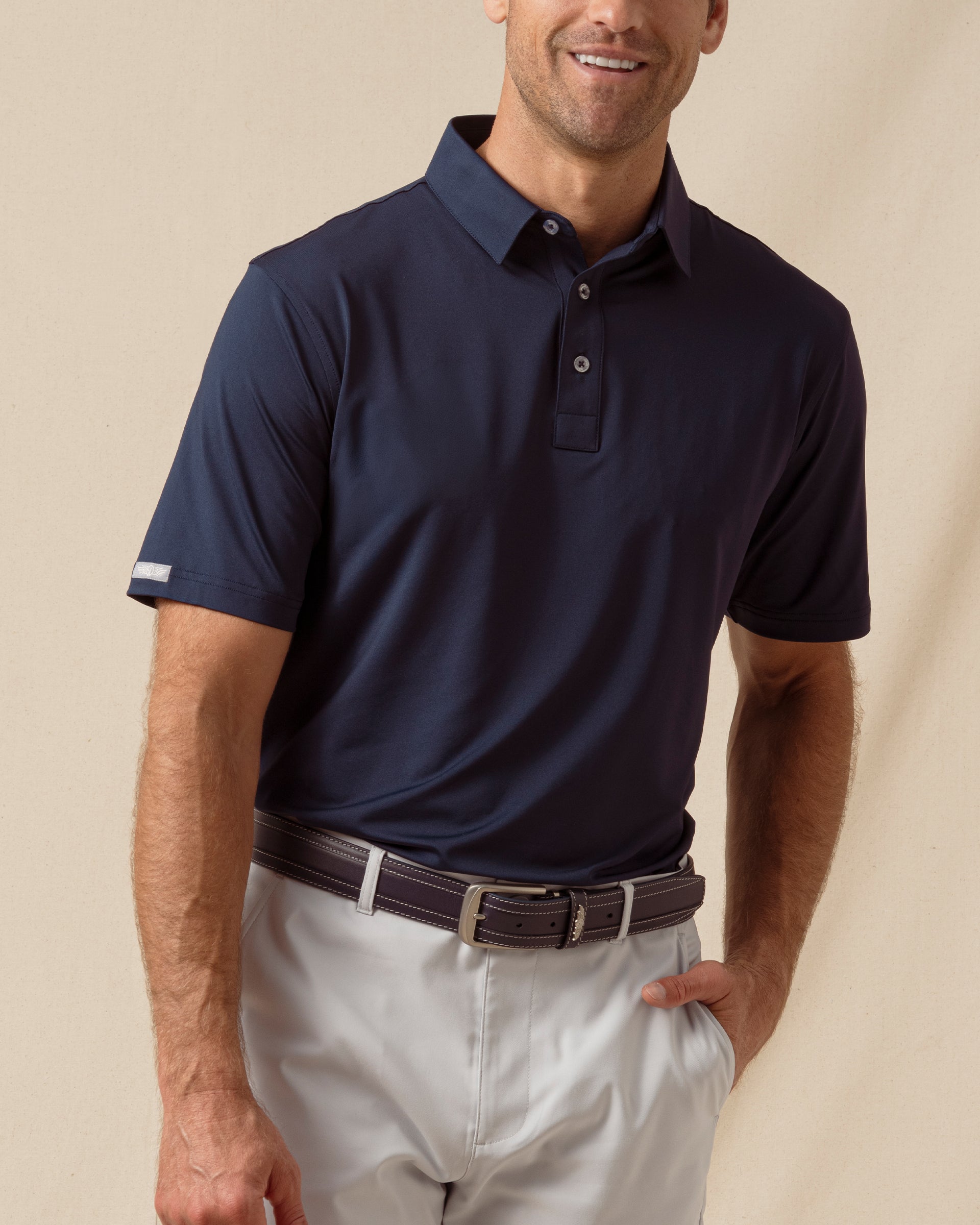 Men’s solid blue polo with short sleeves and button placket, paired with silver shorts