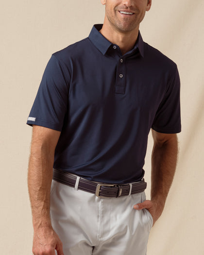 Men’s solid blue polo with short sleeves and button placket, paired with silver shorts