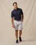 Men’s blue polo styled with silver shorts, brown belt, and blue sneakers