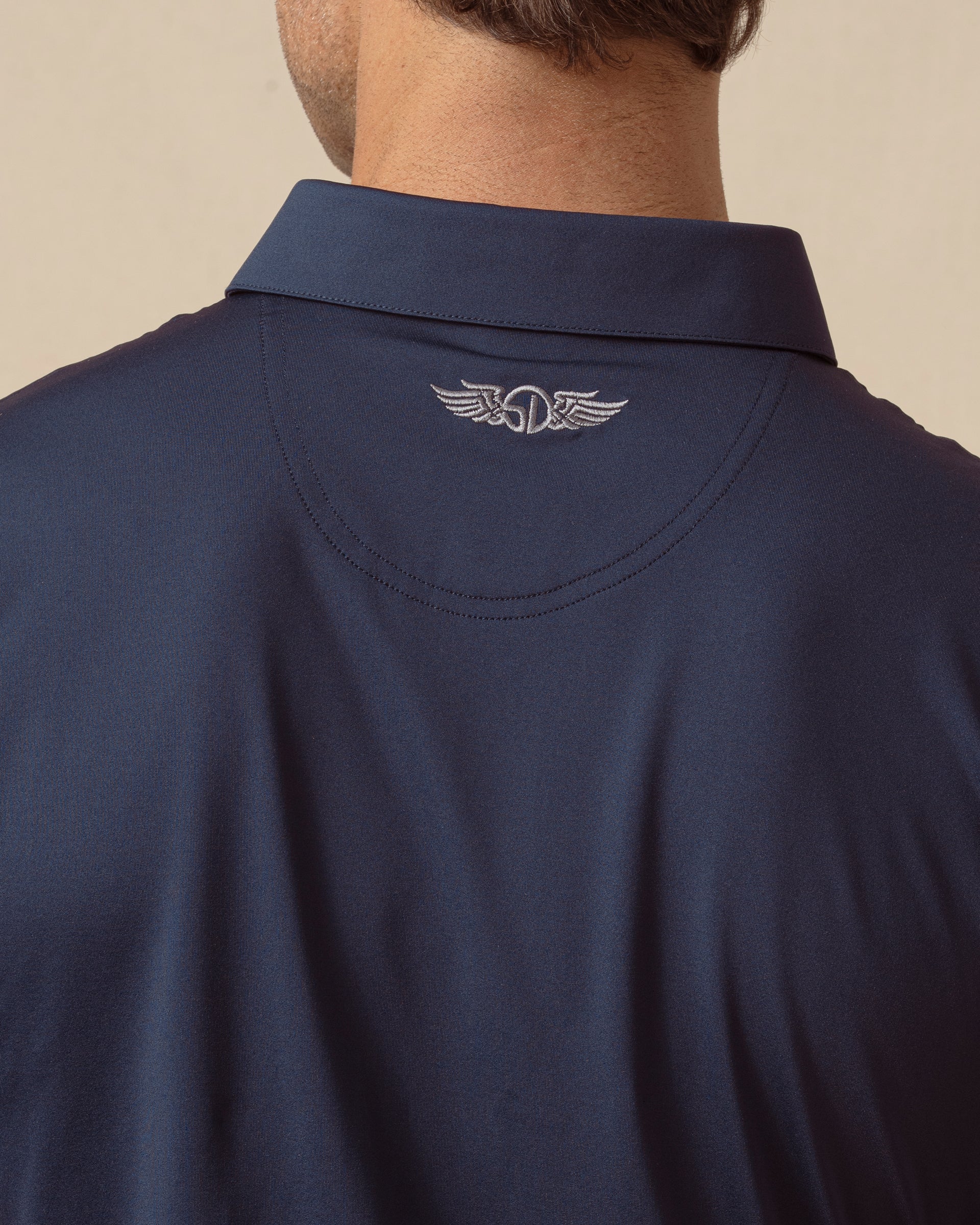 Close-up of men’s blue polo sleeve showing smooth fabric and logo tab detail