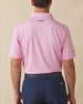Back view of men’s solid pink polo with collar logo detail, tucked into navy shorts