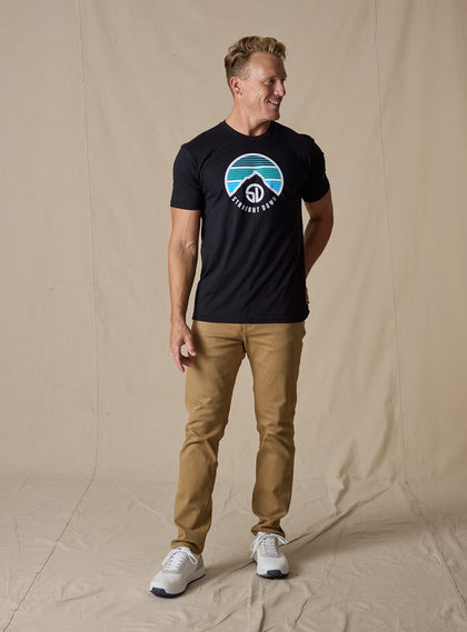 Straight Down Landscape Tee in Black, on model full length view showing black crew neck with mountain graphic paired with tan pants and white golf shoes