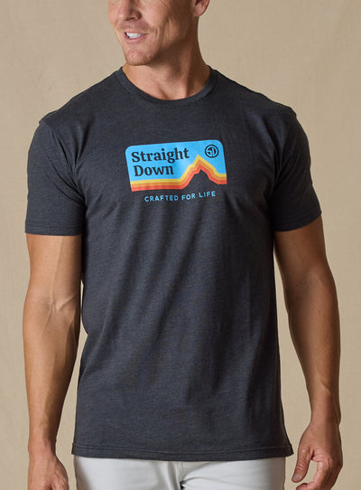 Straight Down Starsky Tee in Charcoal, on model front view showing charcoal heather crew neck with retro mountain graphic and Crafted for Life text paired with white pants
