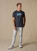Straight Down Starsky Tee in Charcoal, on model full length view showing charcoal heather crew neck with retro graphic paired with white pants and white golf shoes