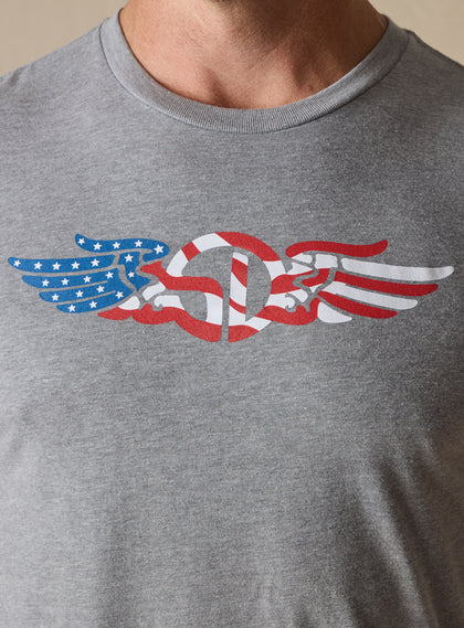 Men's USA Wings Tee in Heather, on model close-up view of the chest featuring an American flag Straight Down logo graphic in red, white, and blue
