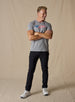 Men's USA Wings Tee in Heather, on model full length front view featuring a heather gray crewneck with an American flag Straight Down logo graphic styled with black pants and white shoes