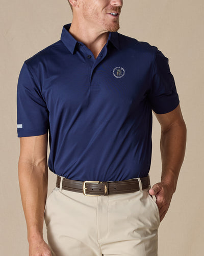Men’s Sullivan Polo in new indigo with 126th U.S. Open Shinnecock Hills logo worn with khaki pants, front view