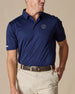 Men’s Sullivan Polo in new indigo with 126th U.S. Open Shinnecock Hills logo worn with khaki pants, front view