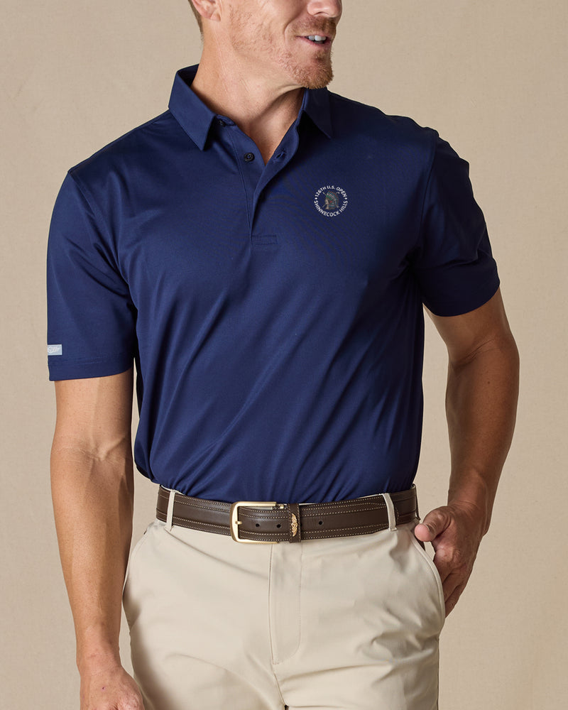 Men’s Sullivan Polo in new indigo with 126th U.S. Open Shinnecock Hills logo worn with khaki pants, front view