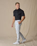 Full-body side view of the Sullivan Polo in Black paired with light gray pants