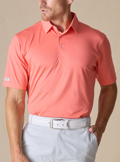 Men’s Sullivan Polo in gala orange styled with light gray golf pants, front view