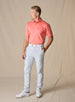 Full-body view of the Sullivan Polo in gala orange paired with light gray golf pants and white golf shoes