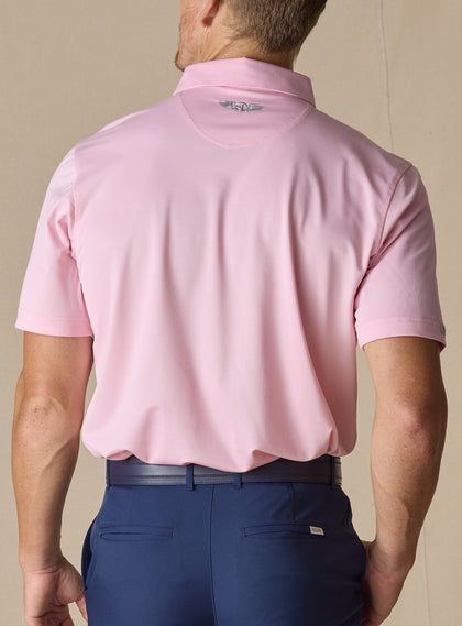 Men’s Sullivan Polo in Pink Lemonade, back view worn with navy golf pants