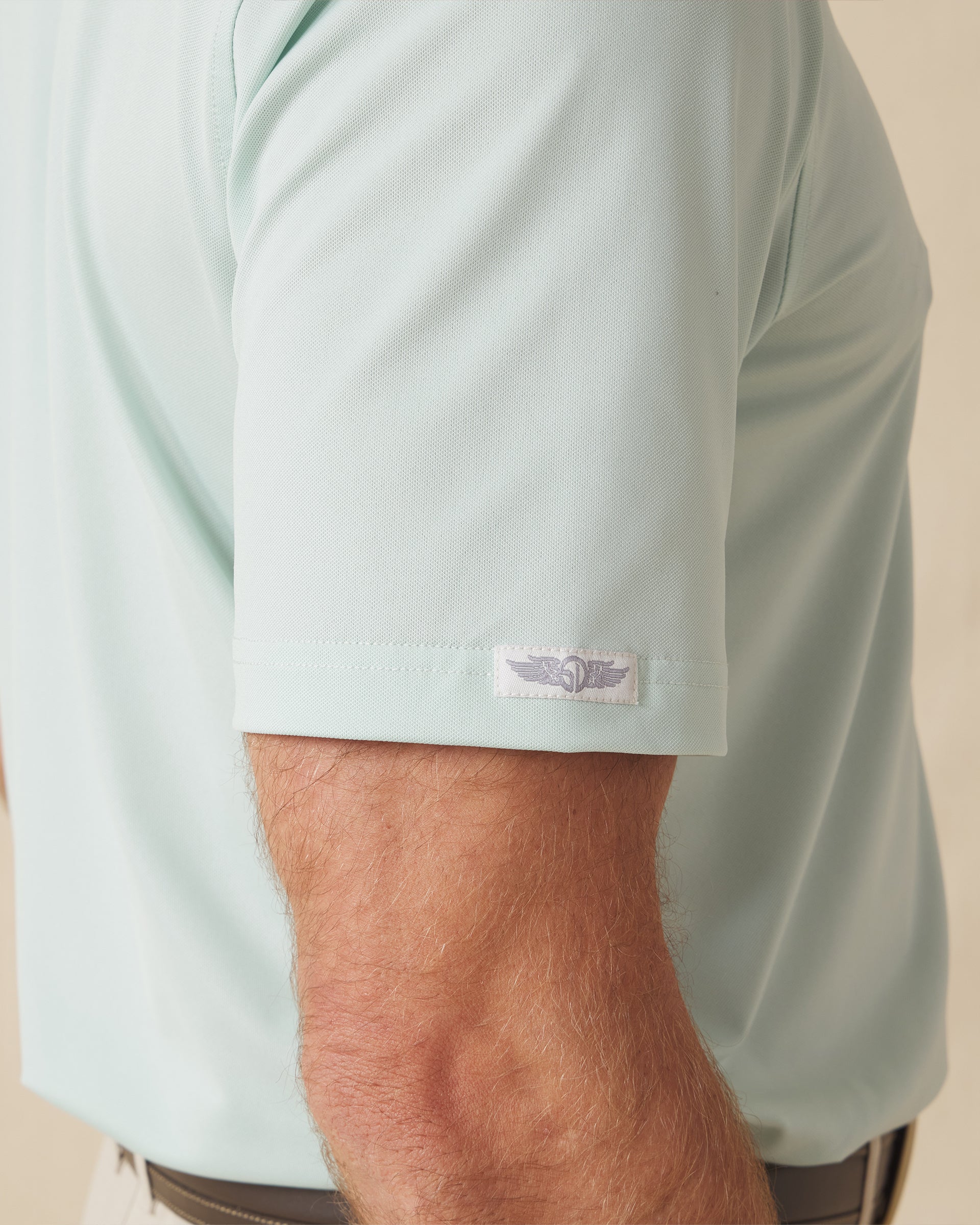 Close-up of the Sullivan Polo sleeve logo tab in celery green