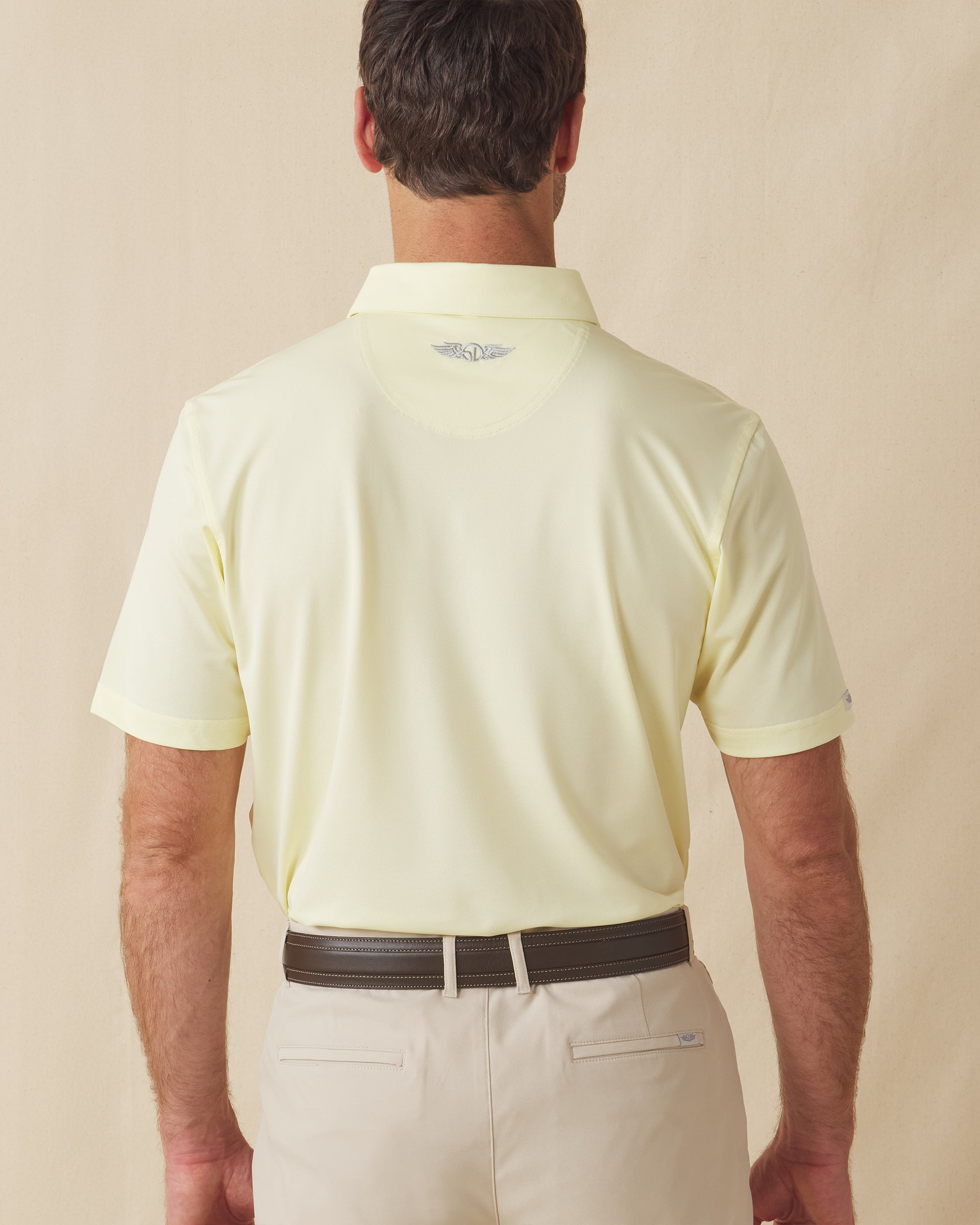 Men’s Sullivan Polo in pale yellow worn with khaki shorts, back view