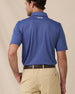 A model shown from the back wearing a blue short-sleeve polo shirt and khaki shorts, photographed against a plain beige studio background.