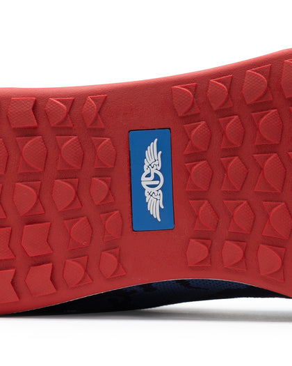 Men's Field V2 Shoe in Camo Indigo, close-up outsole view featuring a red rubber outsole with multi-directional traction lugs and a blue branded logo badge