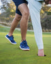 Men's Field V2 Shoe in Camo Indigo, on-course lifestyle view featuring a golfer on the green wearing navy and blue camo print shoes with a white midsole and red outsole