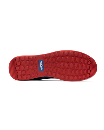 Men's Field V2 Shoe in Camo Indigo, bottom sole view featuring a red rubber outsole with multi-directional traction lugs and a blue branded logo badge