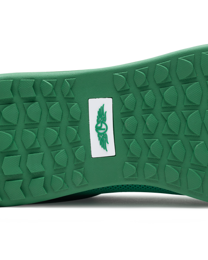 Men's Field V2 Shoe in Green, close-up outsole view featuring a green rubber outsole with multi-directional traction lugs and a white branded logo badge