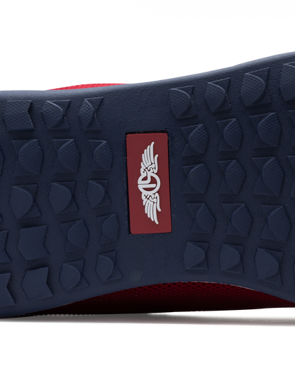 Men's Field V2 Shoe in Red, close-up outsole view featuring a navy rubber outsole with multi-directional traction outsole and a red branded logo badge