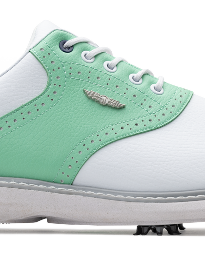 A close-up of a white and mint green golf shoe with white laces, perforated details, a silver wing logo.