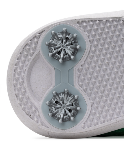 Close-up of the sole of a golf shoe, showing dual metallic cleats on a textured white and light gray outsole.